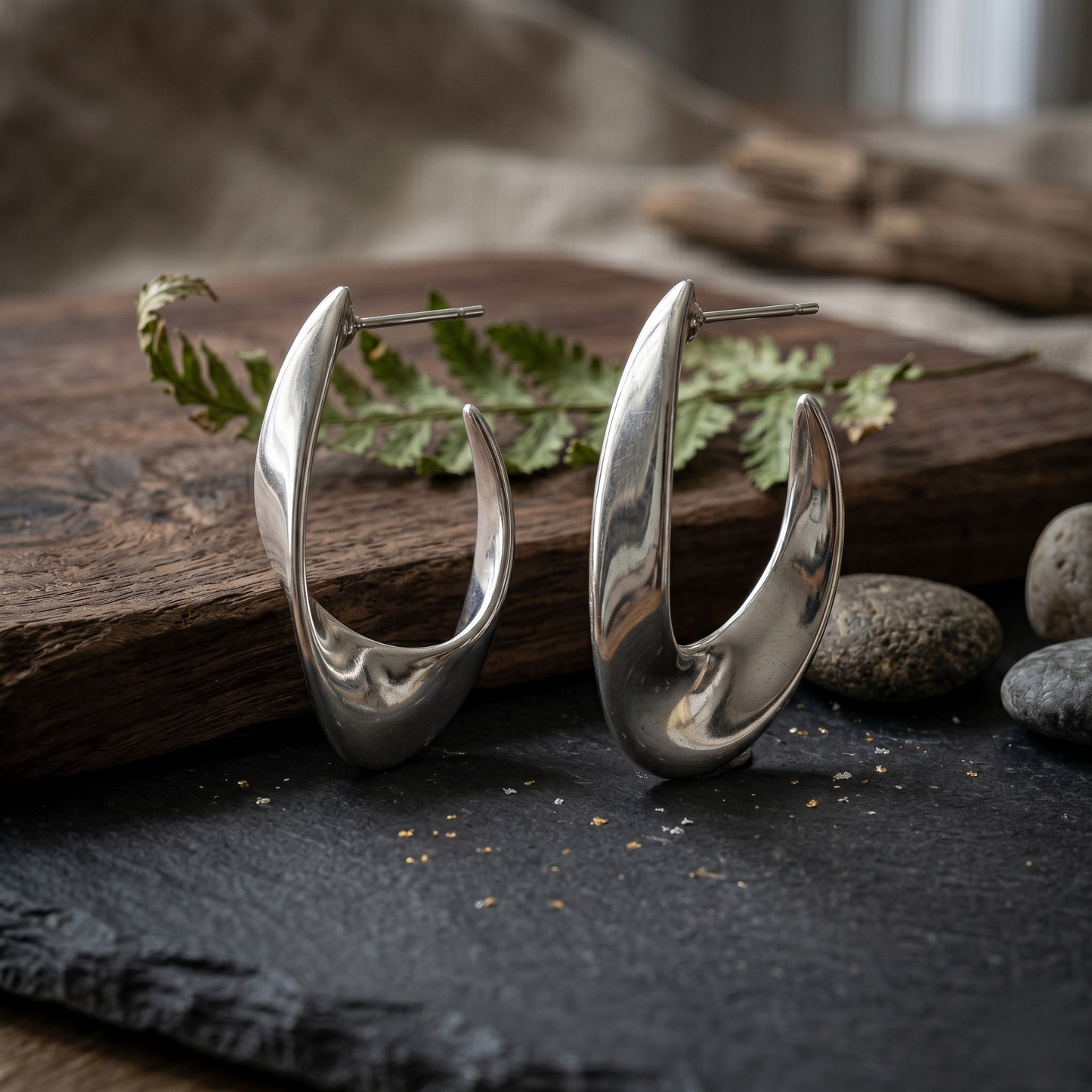Detailed close-up of the Luna Curve sterling silver jewelry hoops in a bright rhodium plated finish, highlighting the sculptural shape and high-polish surface of these contemporary silver earrings.