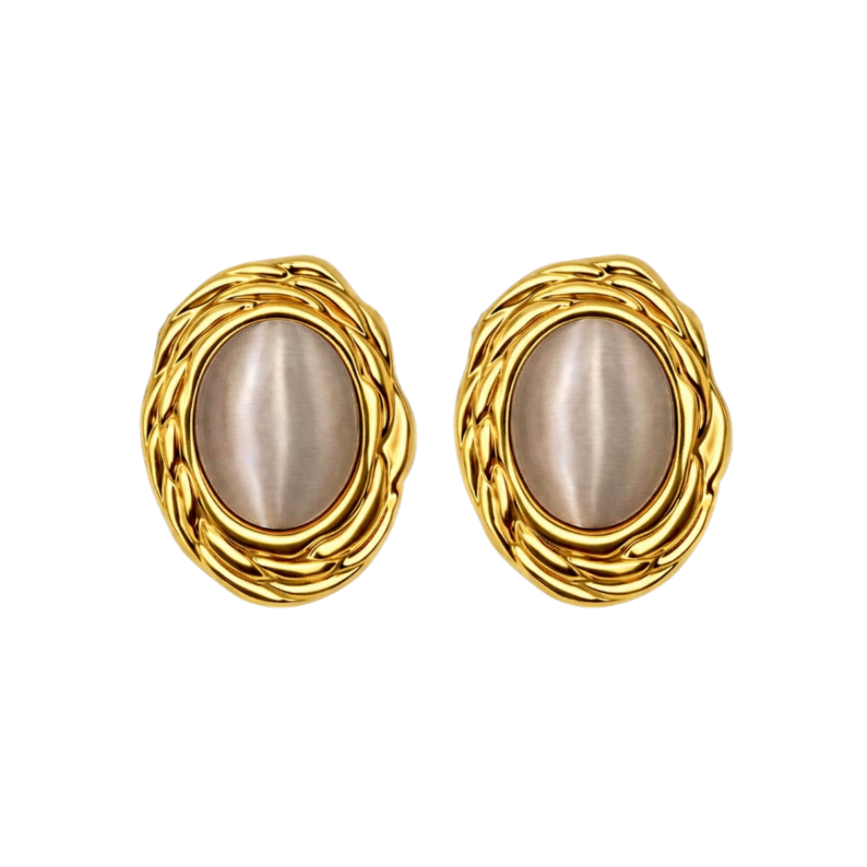 The Gia stud earrings styled on a model, showcasing how the 18k gold plated stainless steel frame and luminous cat’s eye stone catch the light against the skin. The vintage texture and elegant oval shape highlight the luxurious presence of these statement stud earrings when worn.