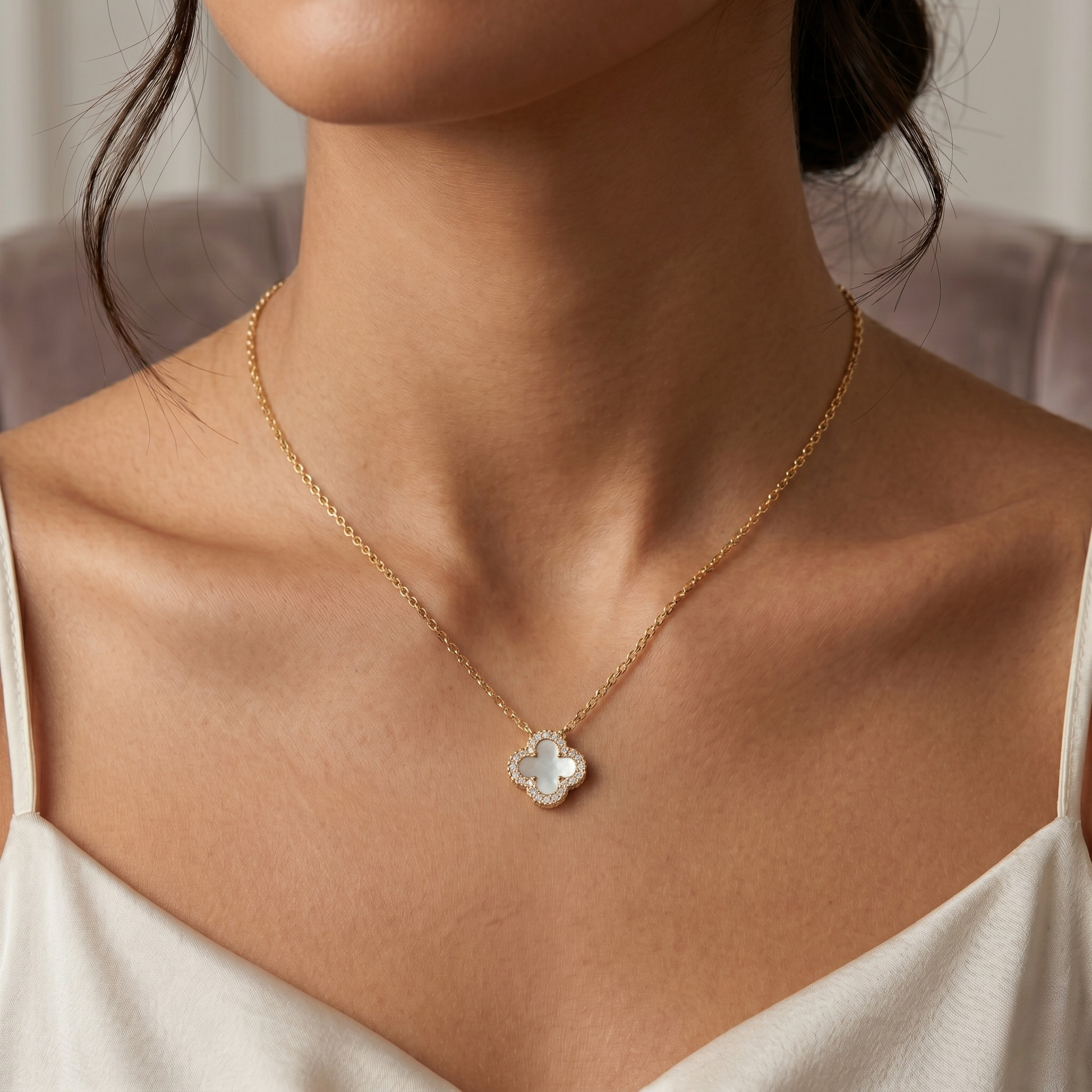 Close up of white clover pendant with zircon border on 18k gold plated sterling silver necklace.